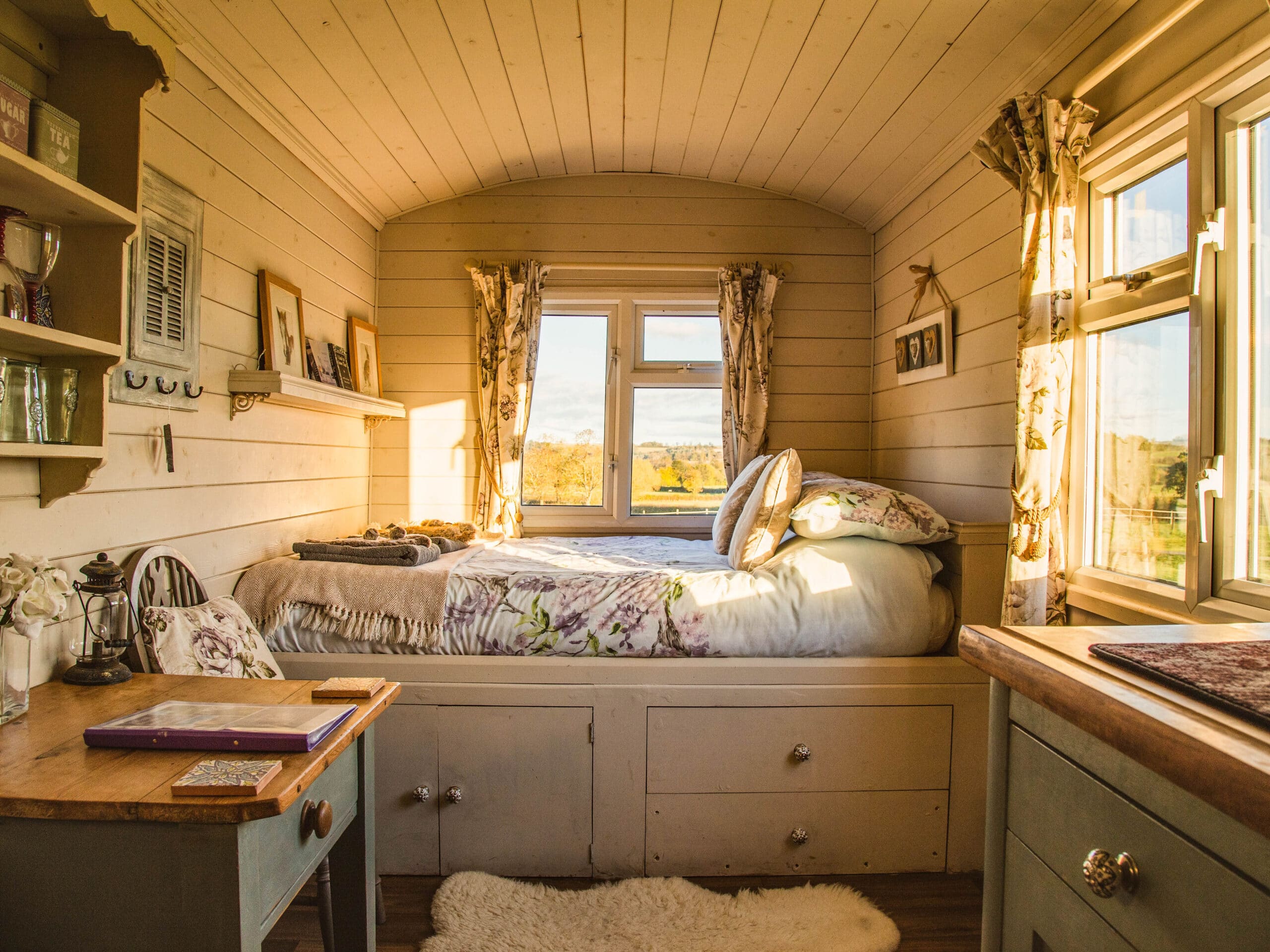 Tiny home shed bedroom with a built-in bed, wooden walls, and large windows allowing natural light to flow in.